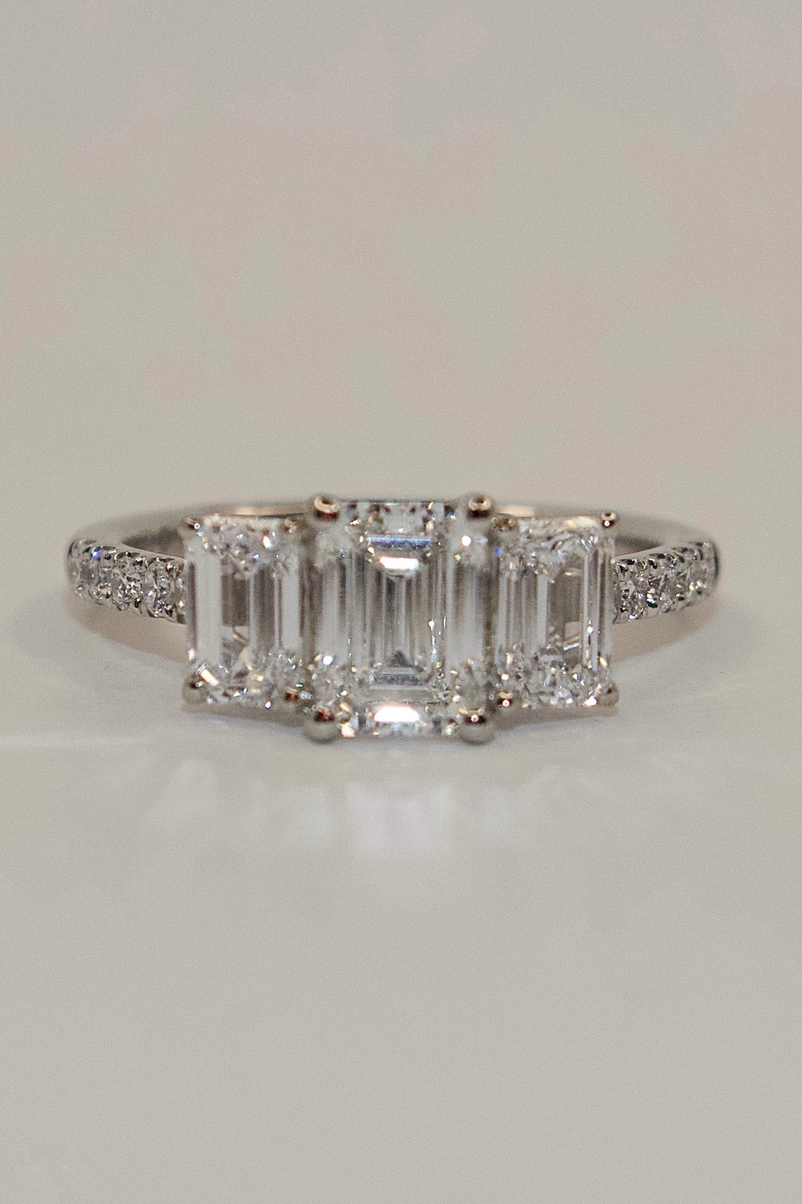 Platinum Three Stone Laboratory Grown Emerald Cut Diamonds with Diamond Band